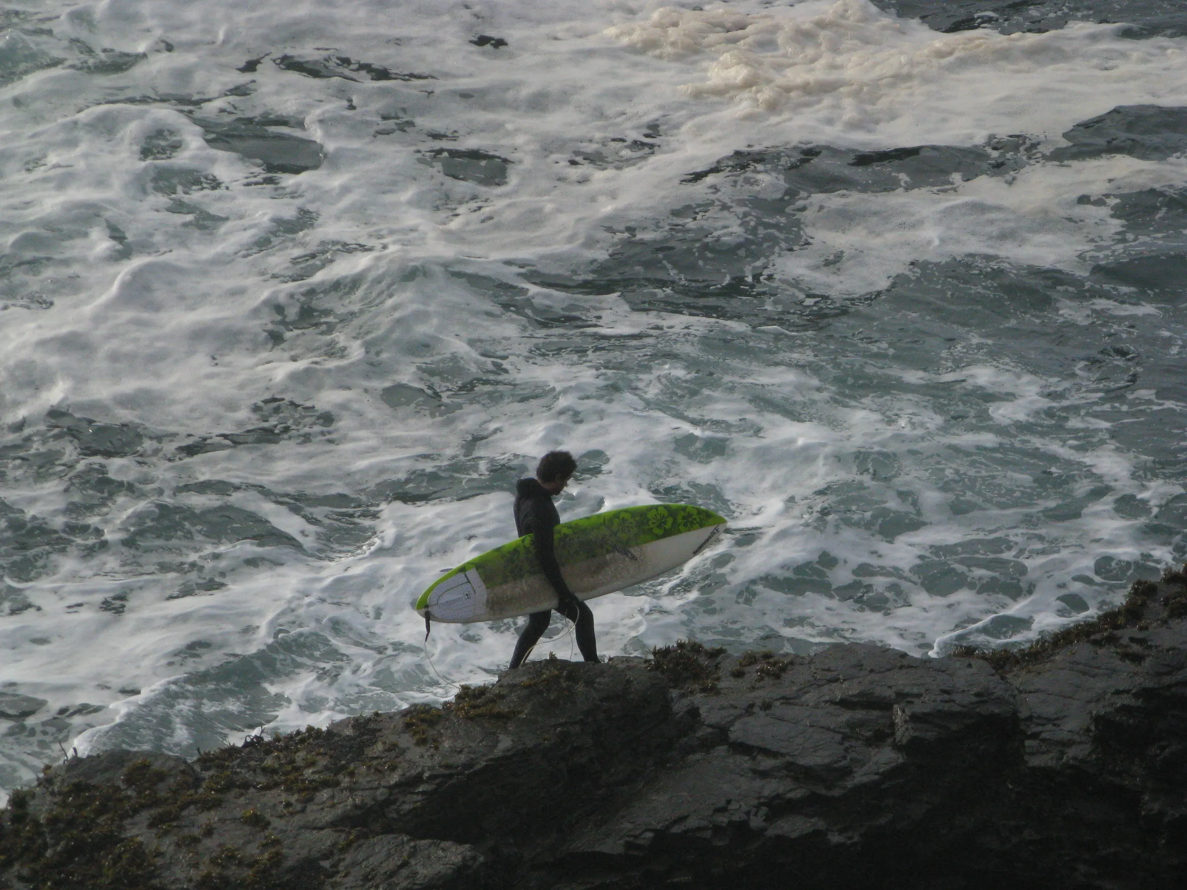 Surfista caminando sobre las rocas de Punta de Lobos, Pichilemu